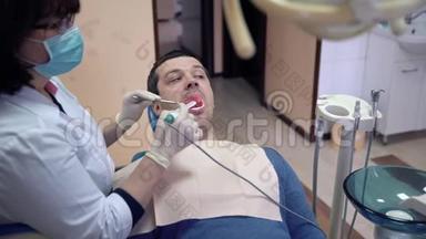 特写女牙医用口内照相机检查病人的牙齿。 牙科疾病的治疗和预防